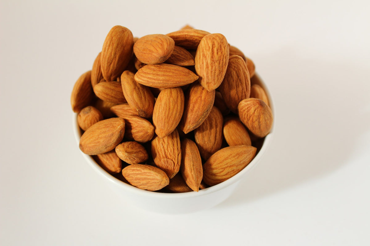 A white bowl full of whole almonds