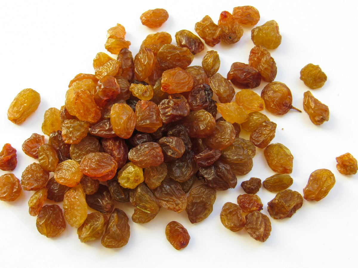 A heap of golden raisins on a white background