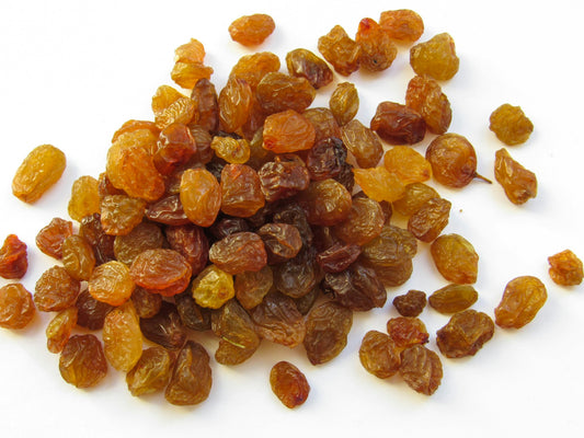 A heap of golden raisins on a white background